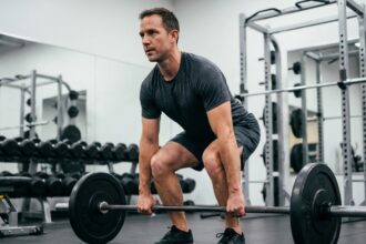 Homme musclé en salle de sport soulevant une barre