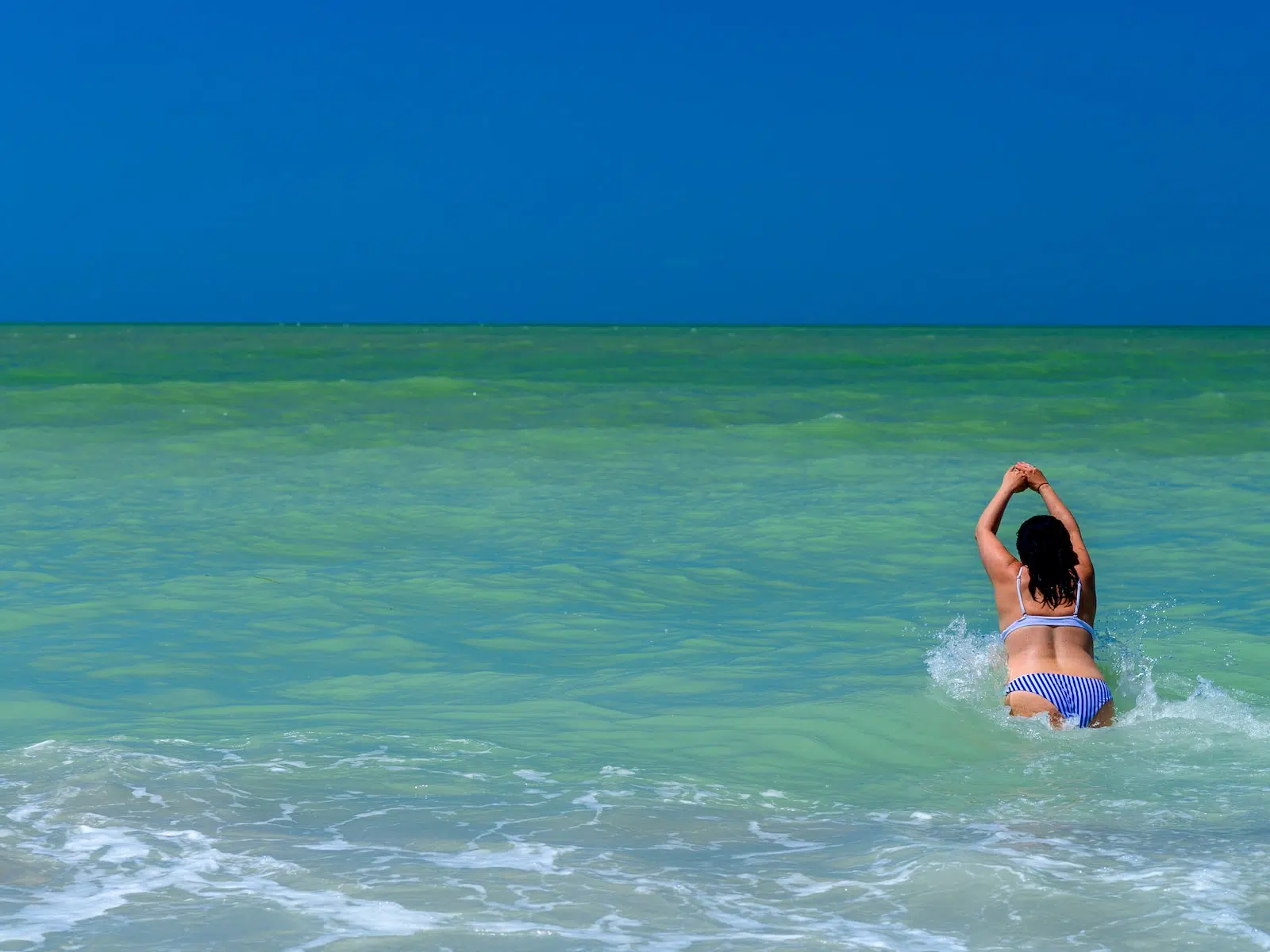 woman in blue and white bikini top on water during daytime